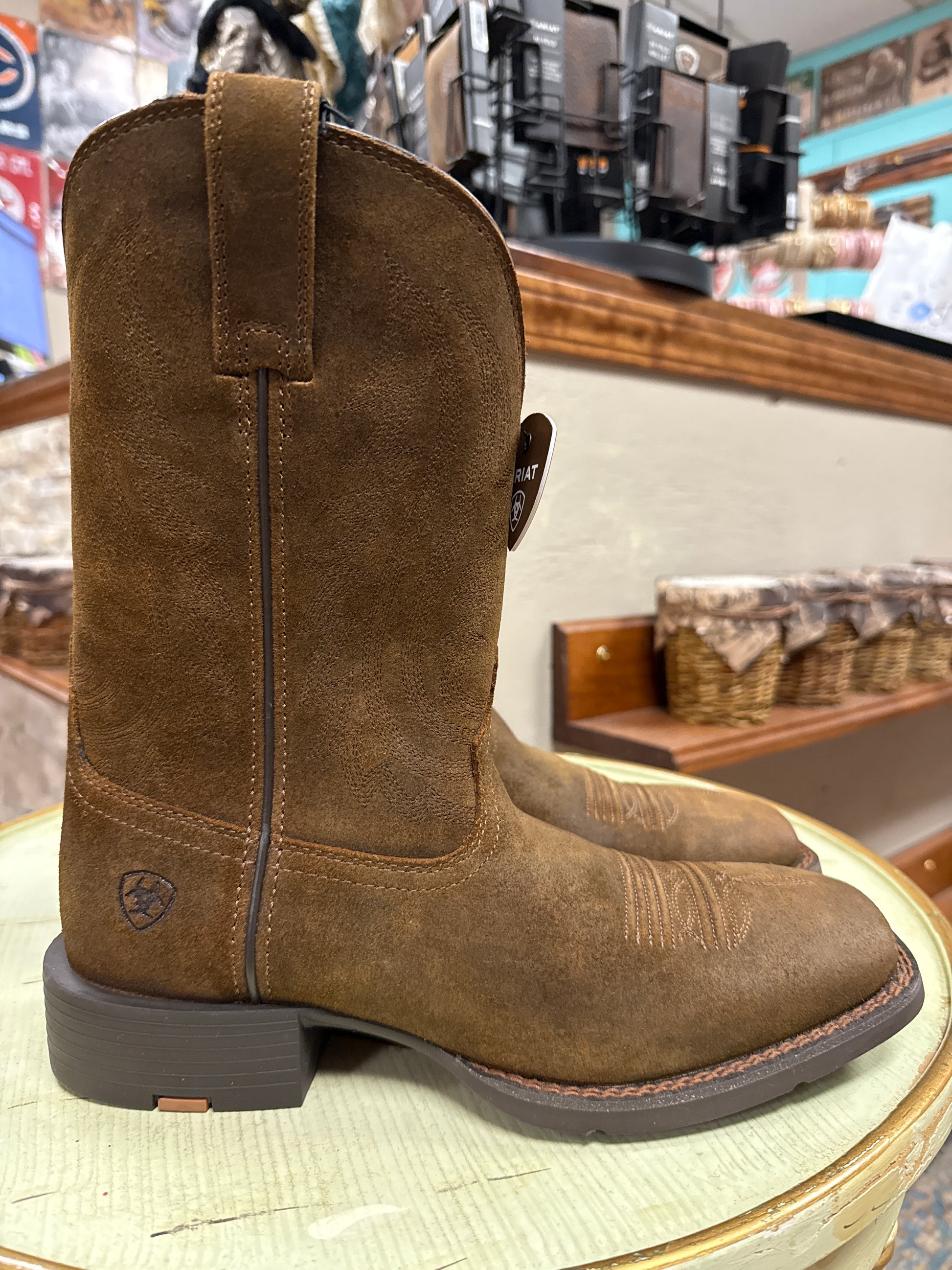 Brown boot with a visible brand logo on a blurred store background
