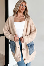 Woman wearing a beige knitted cardigan over a white top and blue jeans.