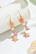 Pair of earrings with starfish and shell charms on a white surface