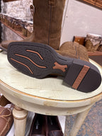 Close-up of a brown leather shoe sole with 'Kerrits' branding on a wooden stool.