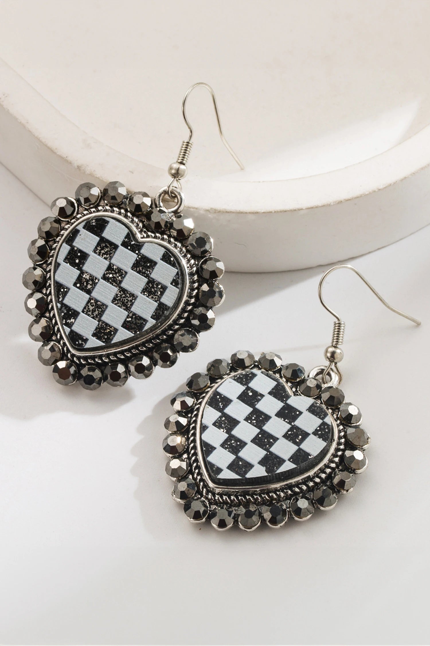 Heart-shaped earrings with checkered design and decorative elements on a white background