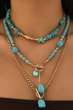 Layered necklaces with turquoise beads and gold chains on a person's neck.