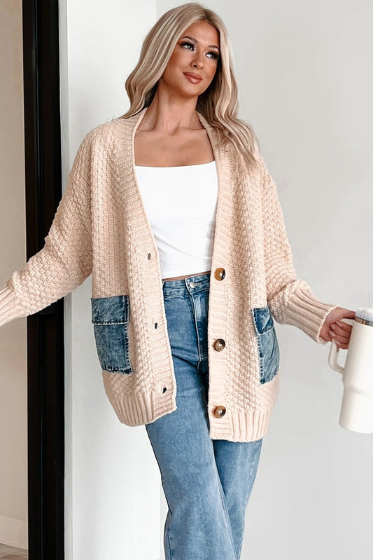 Woman wearing a beige cardigan with denim pockets, holding a white mug.