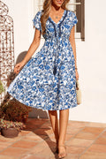 Woman wearing a blue floral dress standing on a patio.