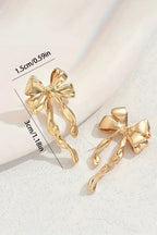 Gold bow-shaped earrings with measurements on a light background