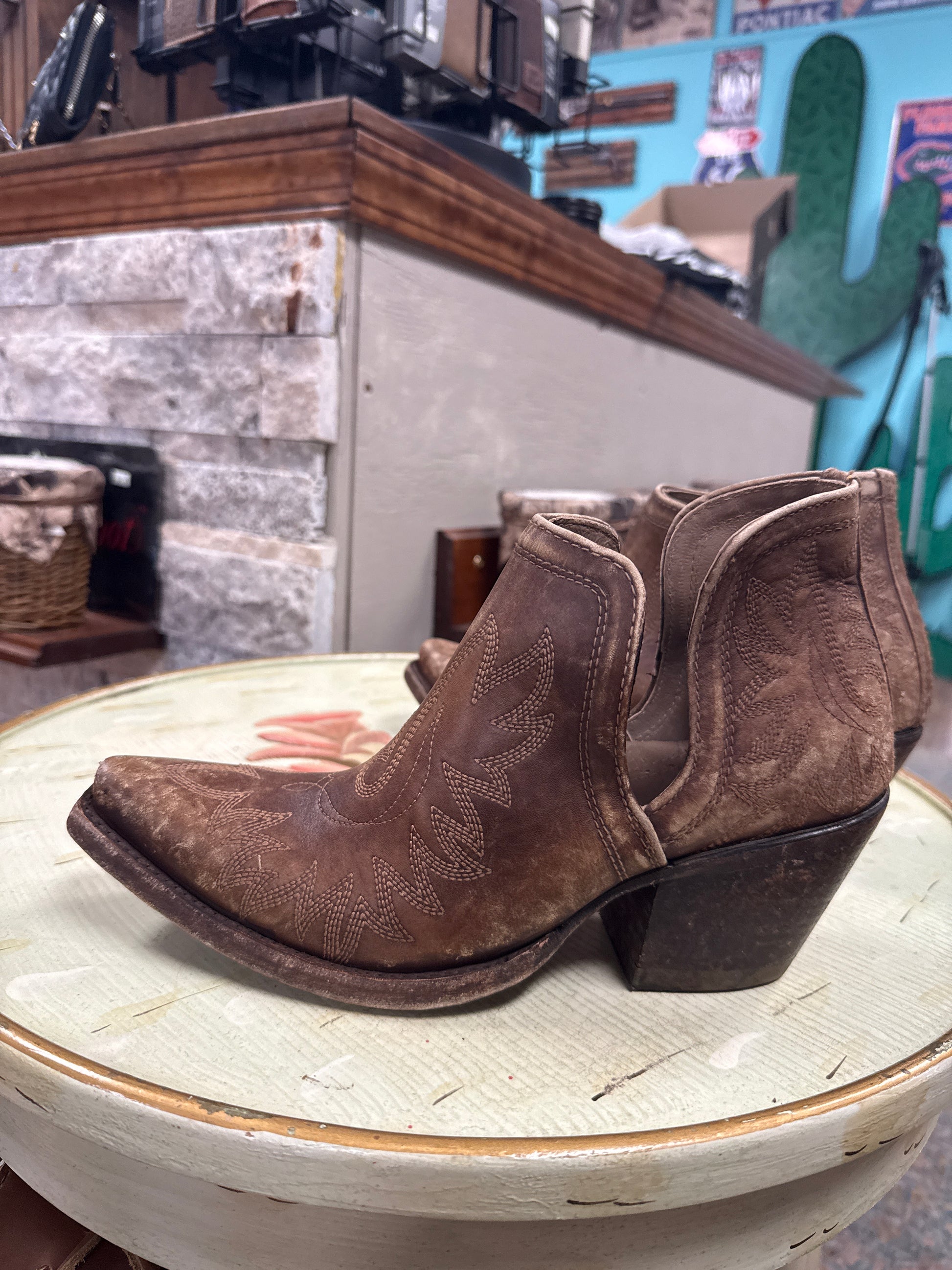Brown cowboy boot on a wooden block with a blurred background