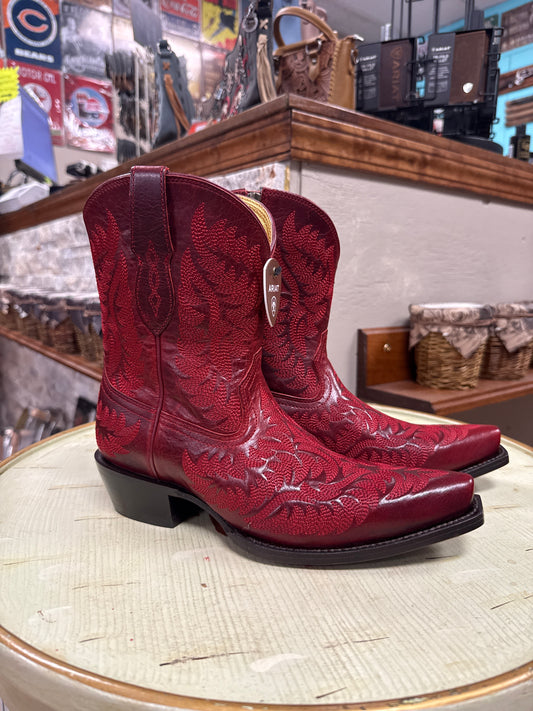 Red cowboy boots on a wooden surface with a store interior background