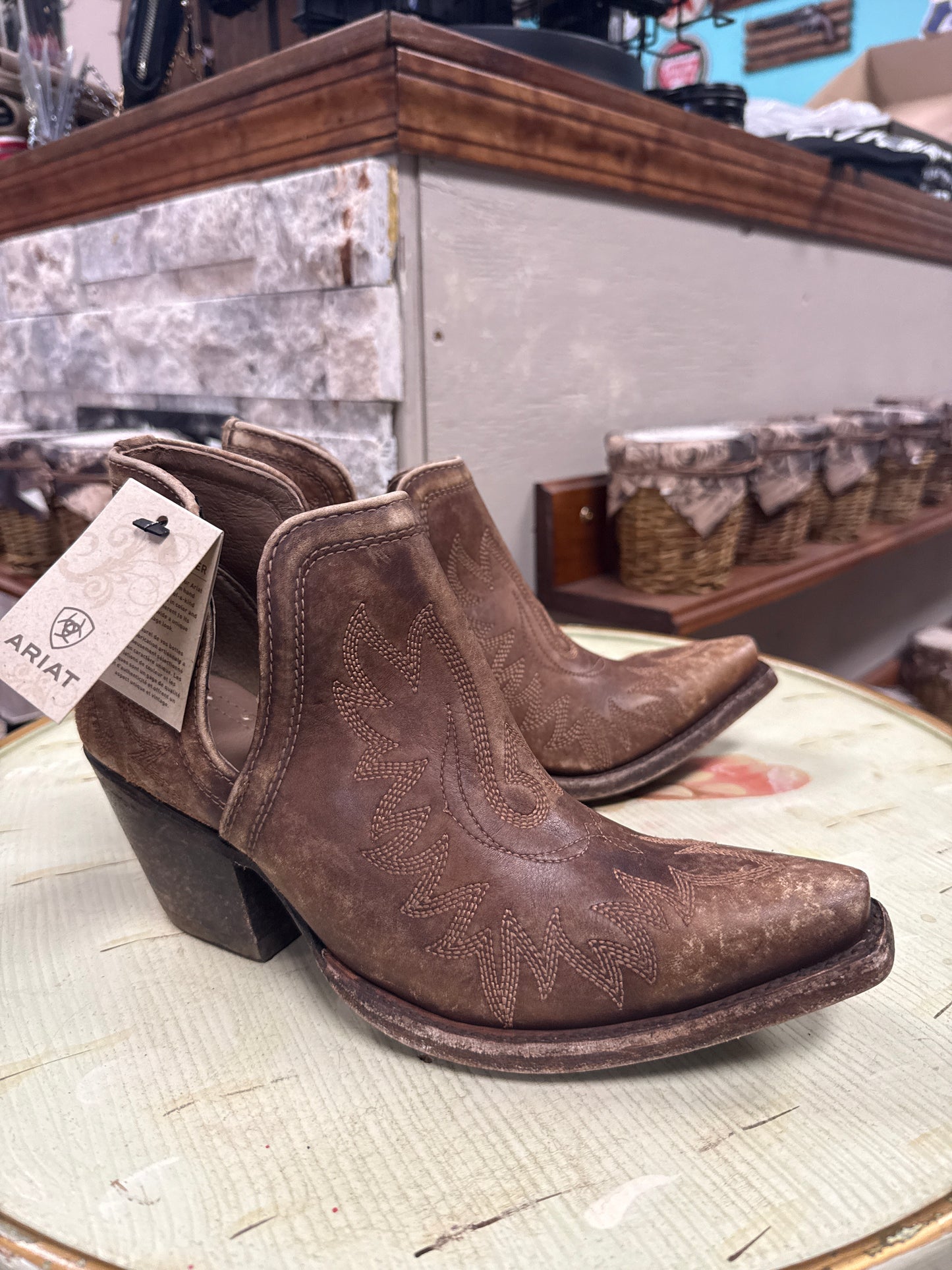 Brown cowboy boots with Ariat tag on a wooden surface