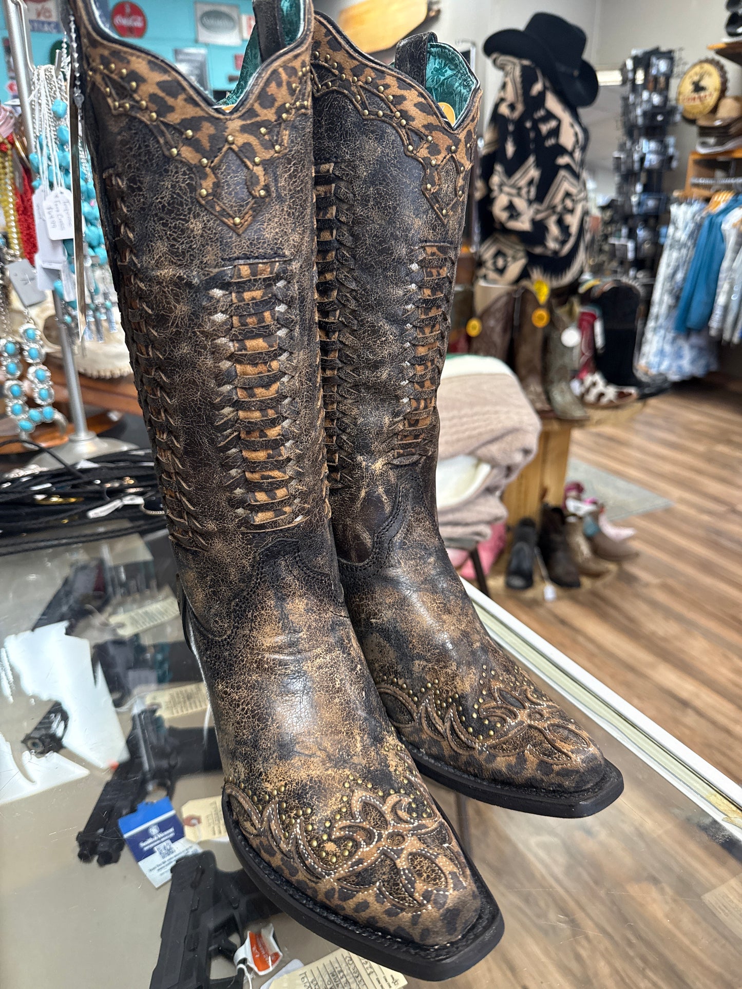 Pair of black and brown cowboy boots with detailed design on a store shelf.