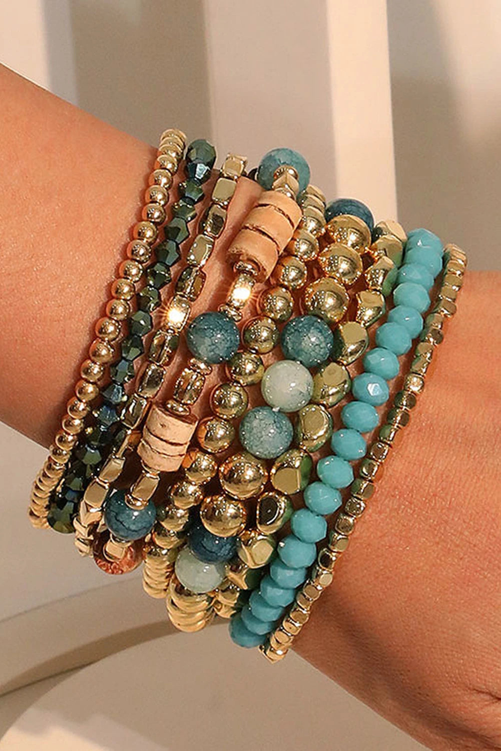 Stack of colorful beaded bracelets on a wrist against a neutral background