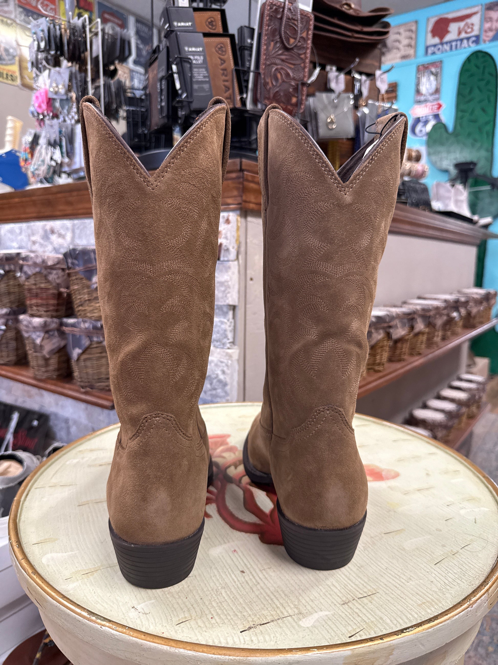 Brown suede boots on a light-colored surface with a store interior in the background
