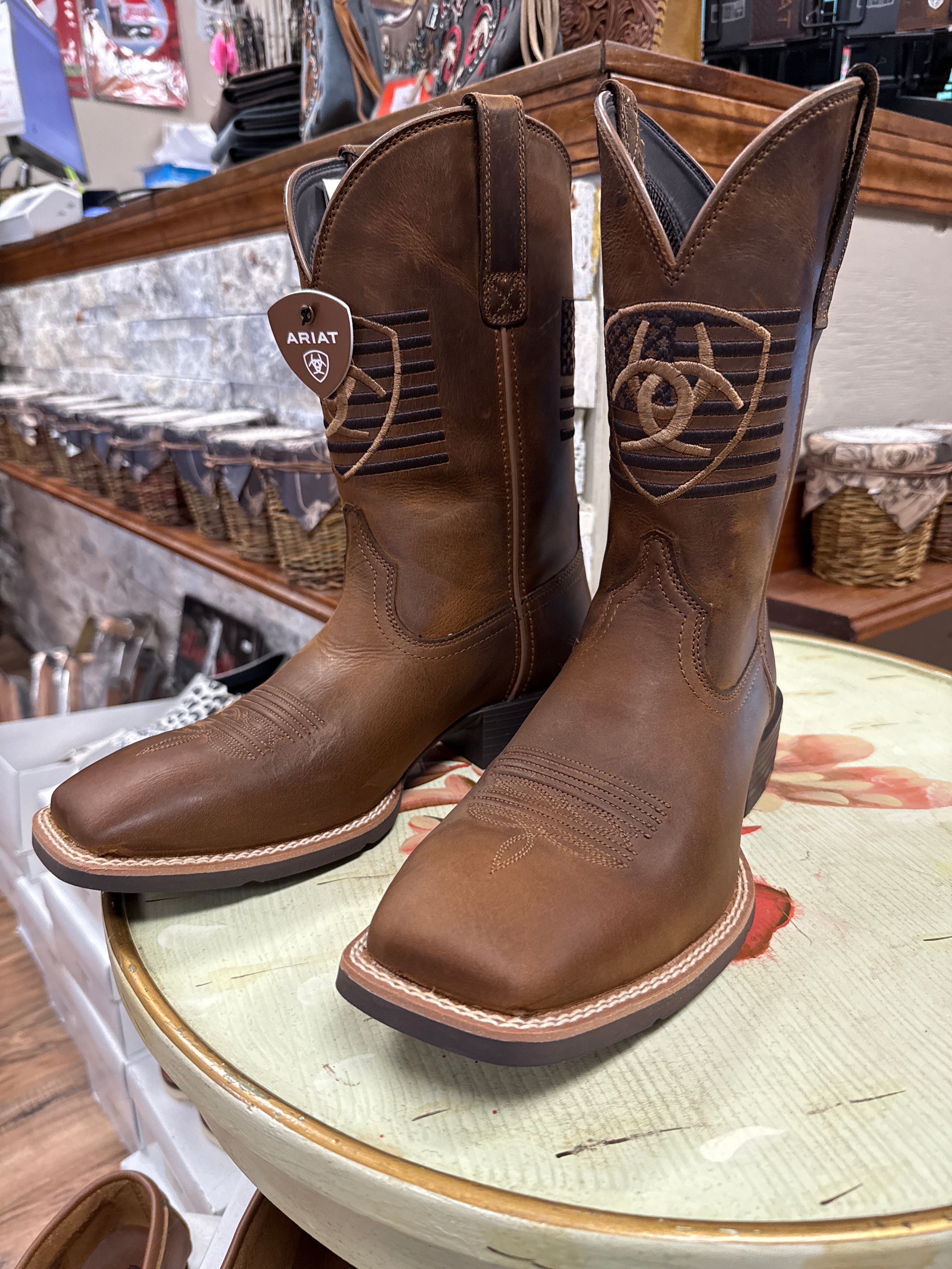 Brown leather boots with Ariat logo on a round surface