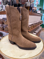 Brown suede boots on a wooden block with a store interior in the background