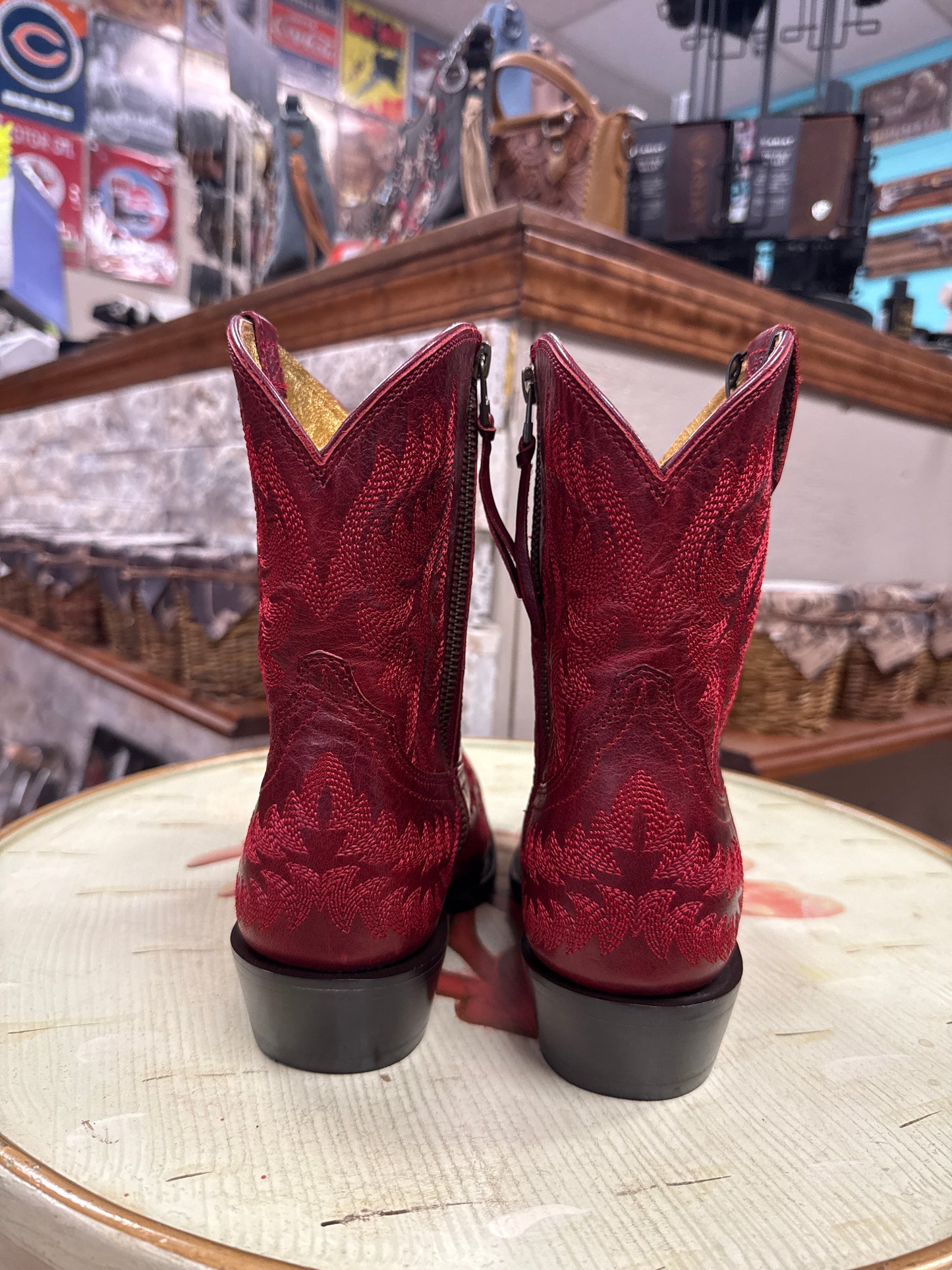 Pair of red cowboy boots on a round surface with a blurred background