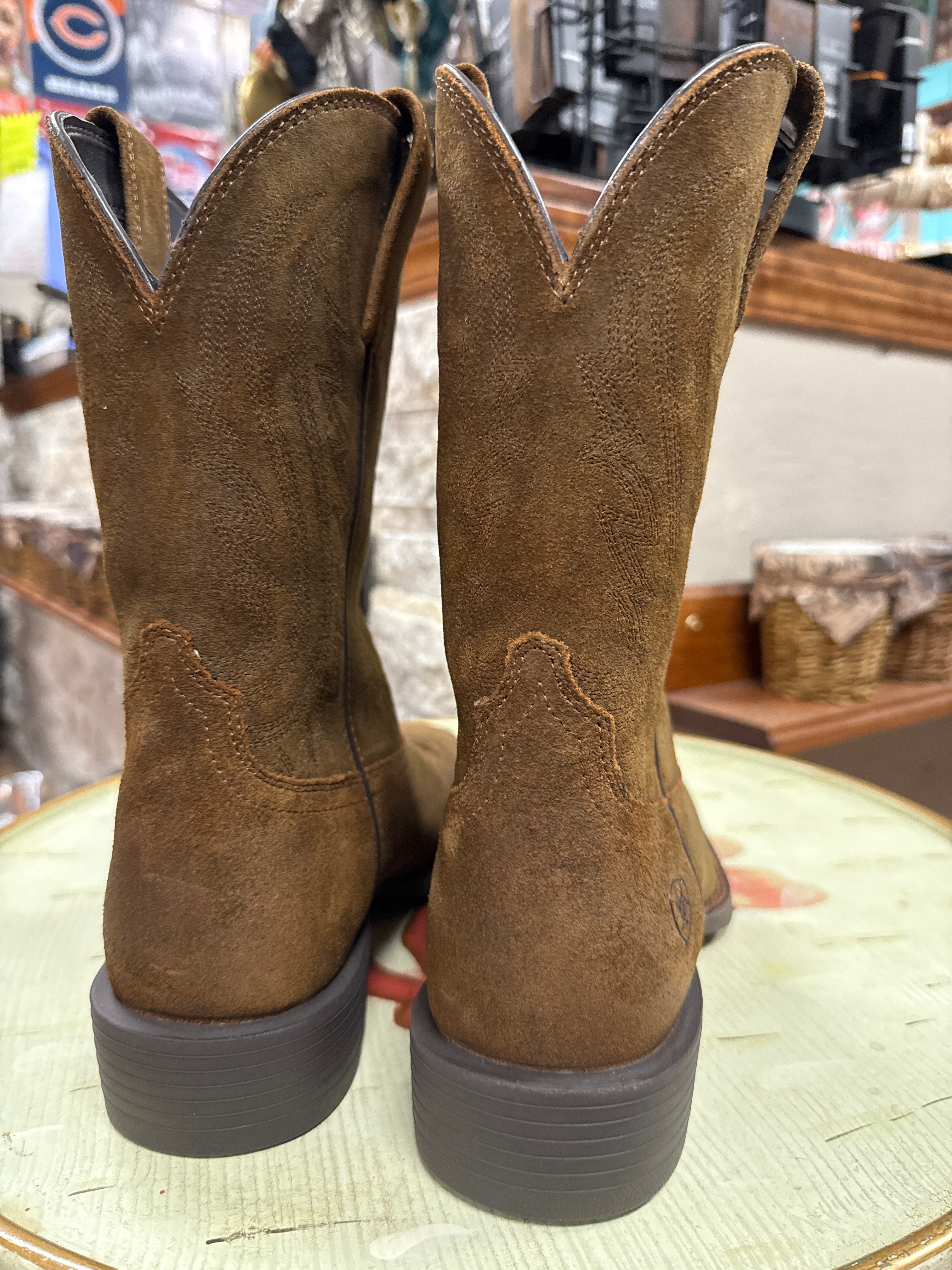 Pair of brown suede boots on a wooden surface with a blurred background
