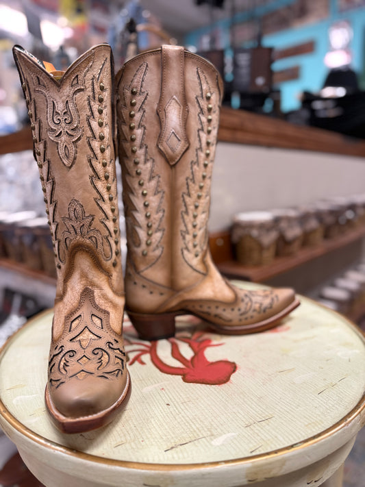 Pair of brown cowboy boots with intricate designs on a wooden stool.