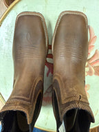 Pair of brown leather boots on a floral-patterned surface