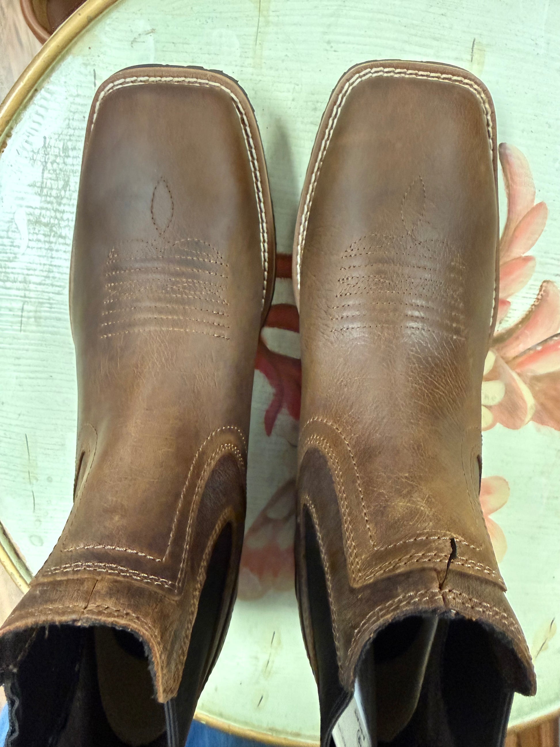 Pair of brown leather boots on a floral-patterned surface