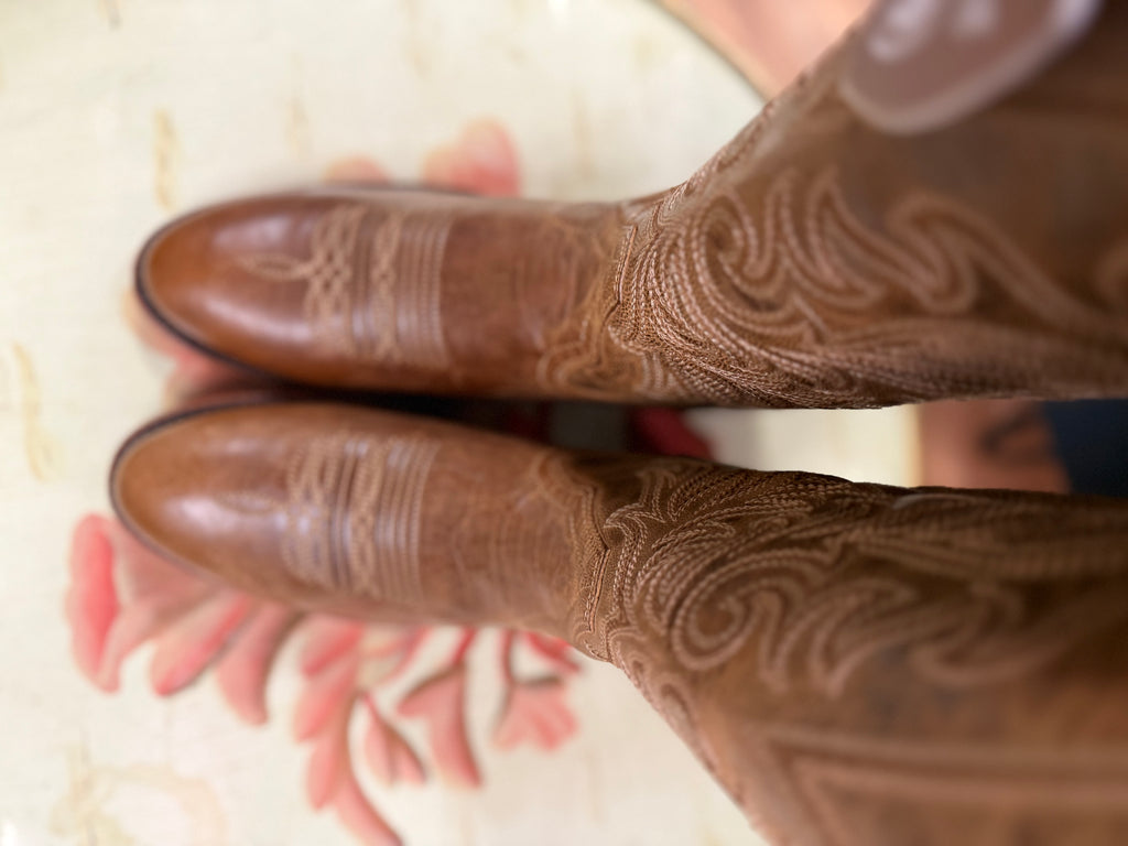 Close-up of brown leather shoes with intricate patterns on a floral background