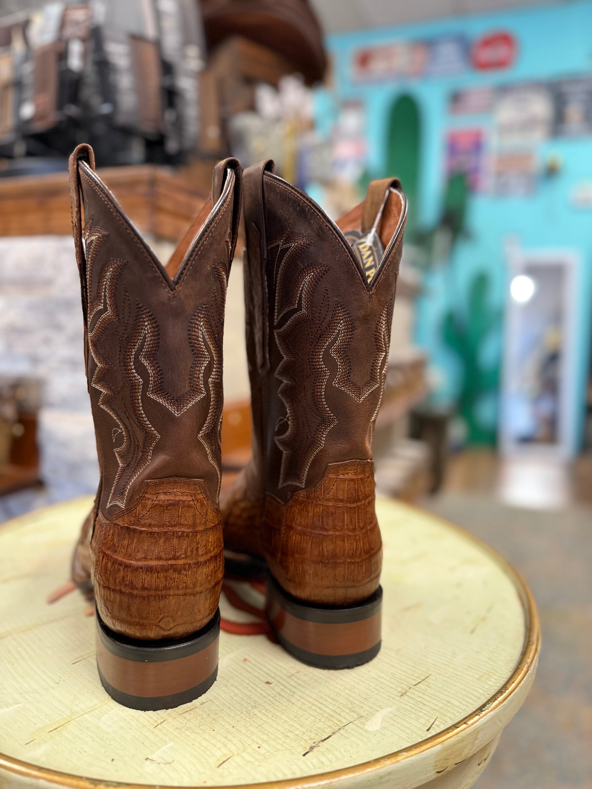 Brown cowboy boots on a woven surface with a blurred store interior in the background