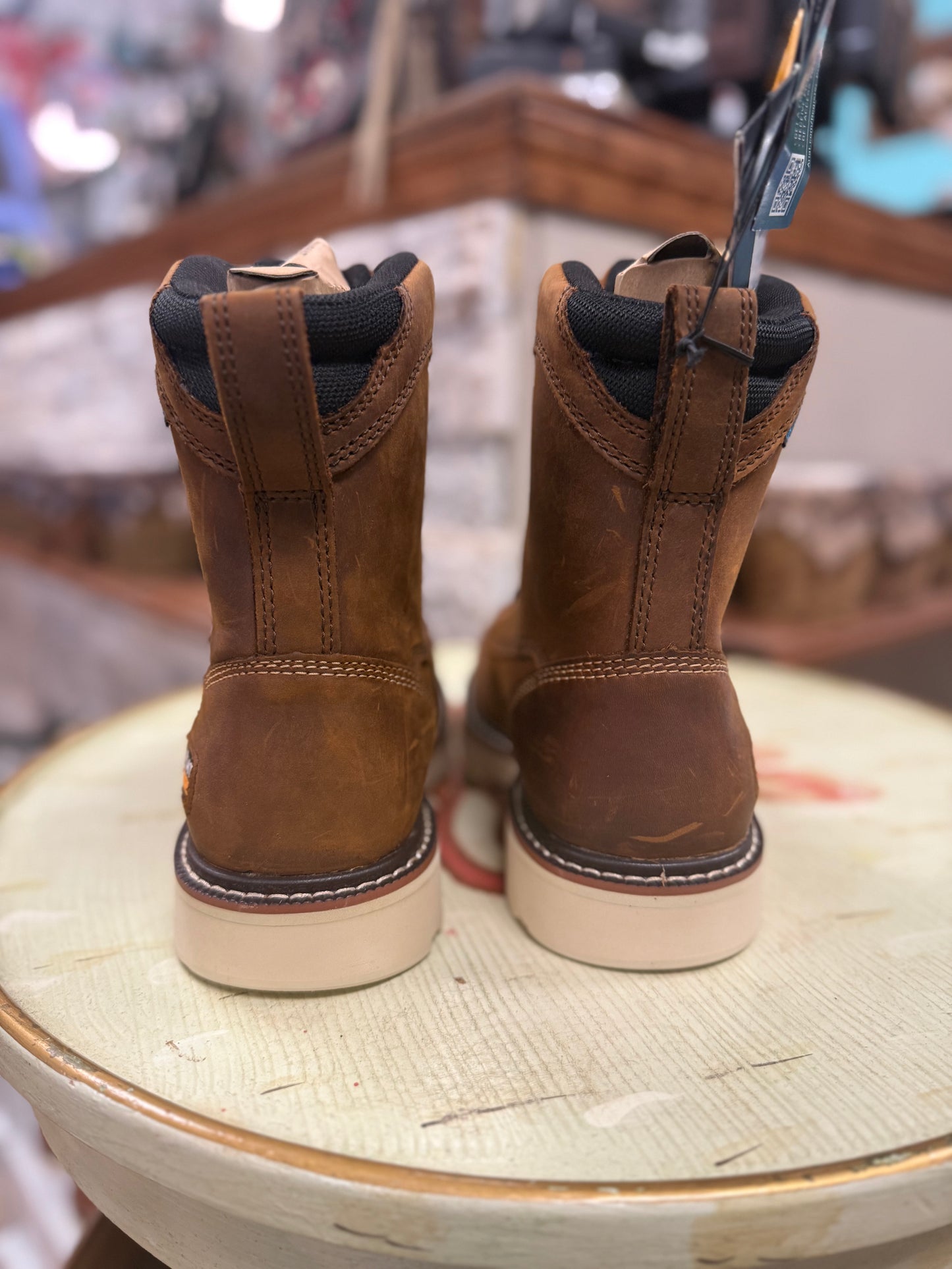 Pair of brown leather boots with black soles on a wooden surface.