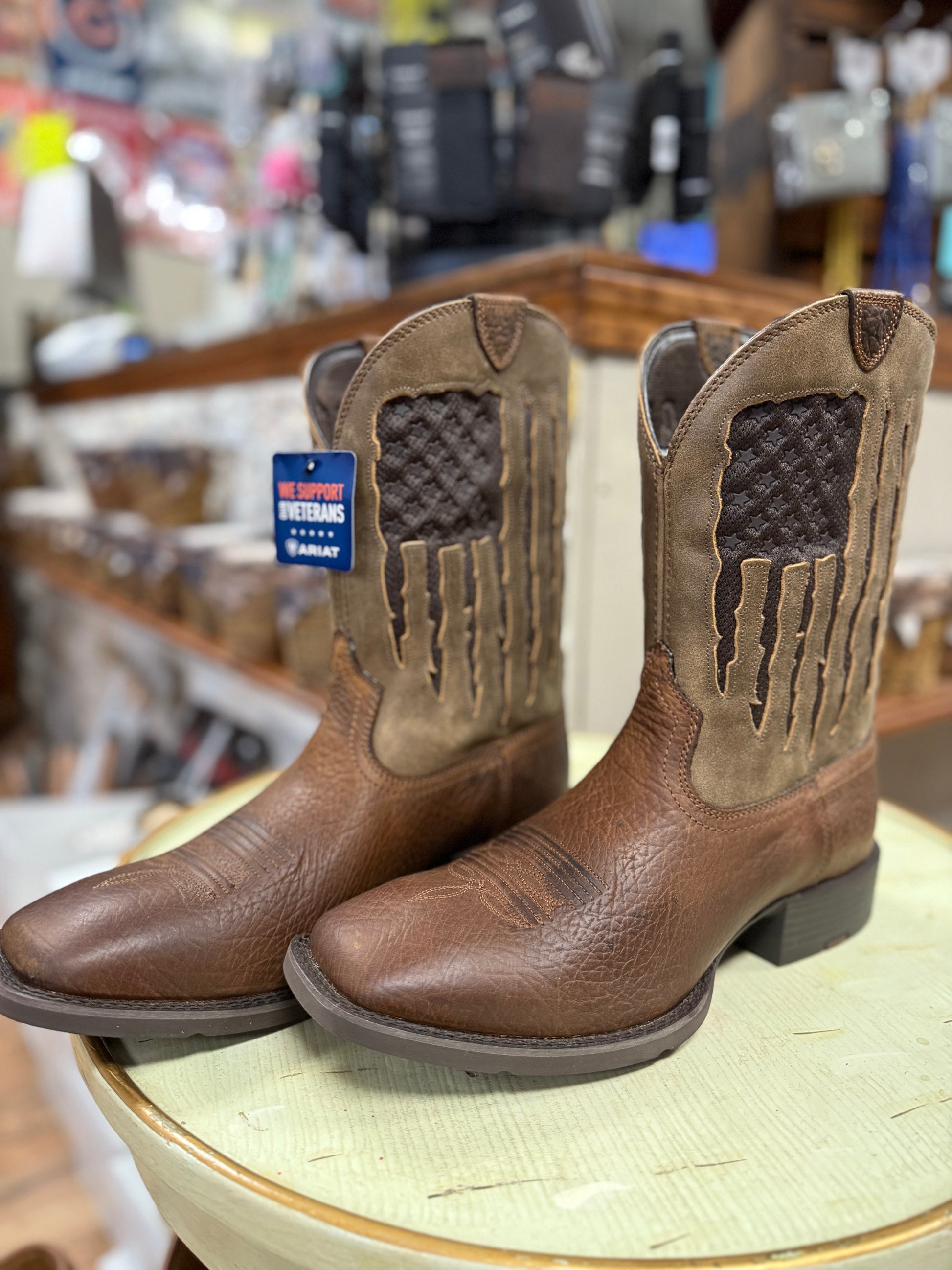 Pair of brown cowboy boots on a display table with a blurred store background