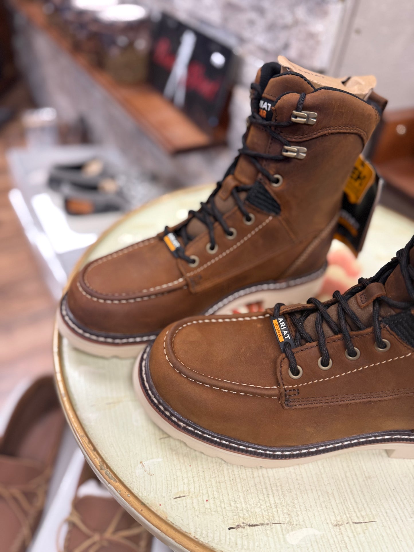 Pair of brown work boots on a round table with blurred background