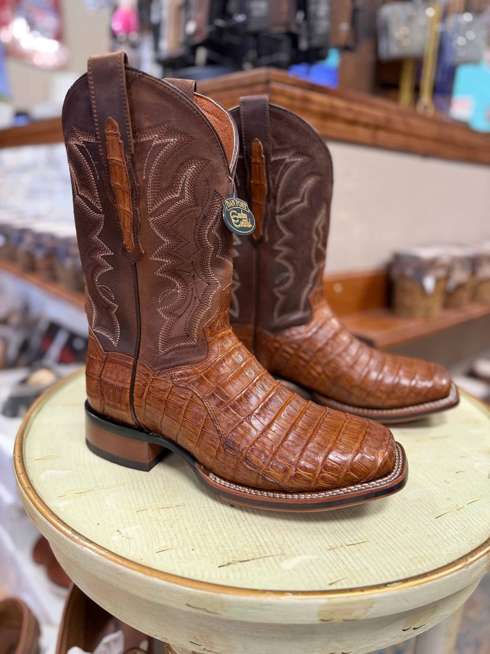 Brown cowboy boots on a round surface with a store setting in the background