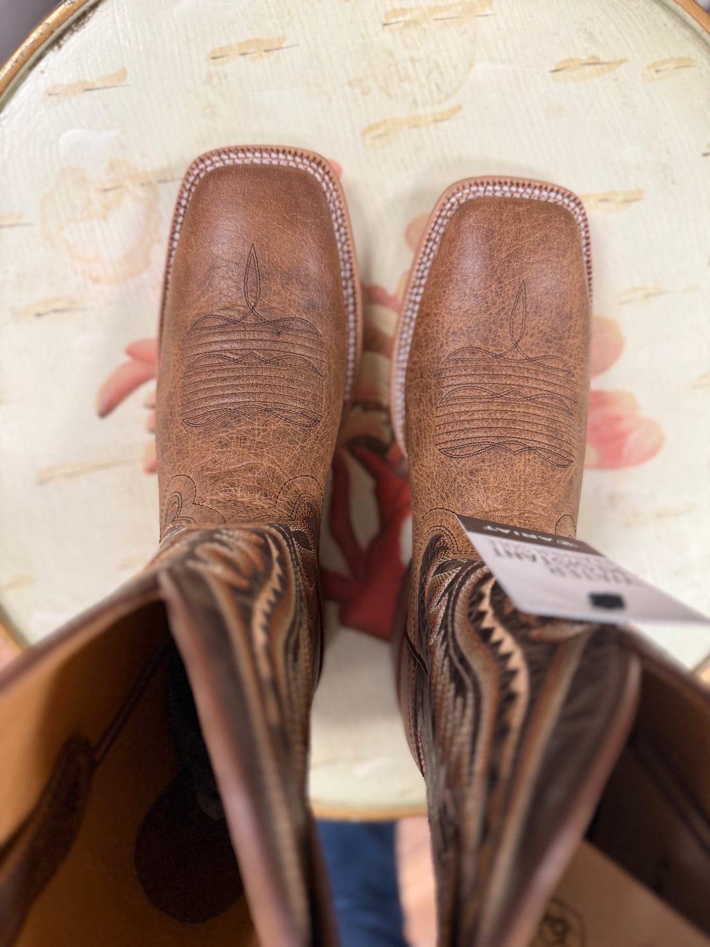Brown leather boots with intricate designs held in a box.