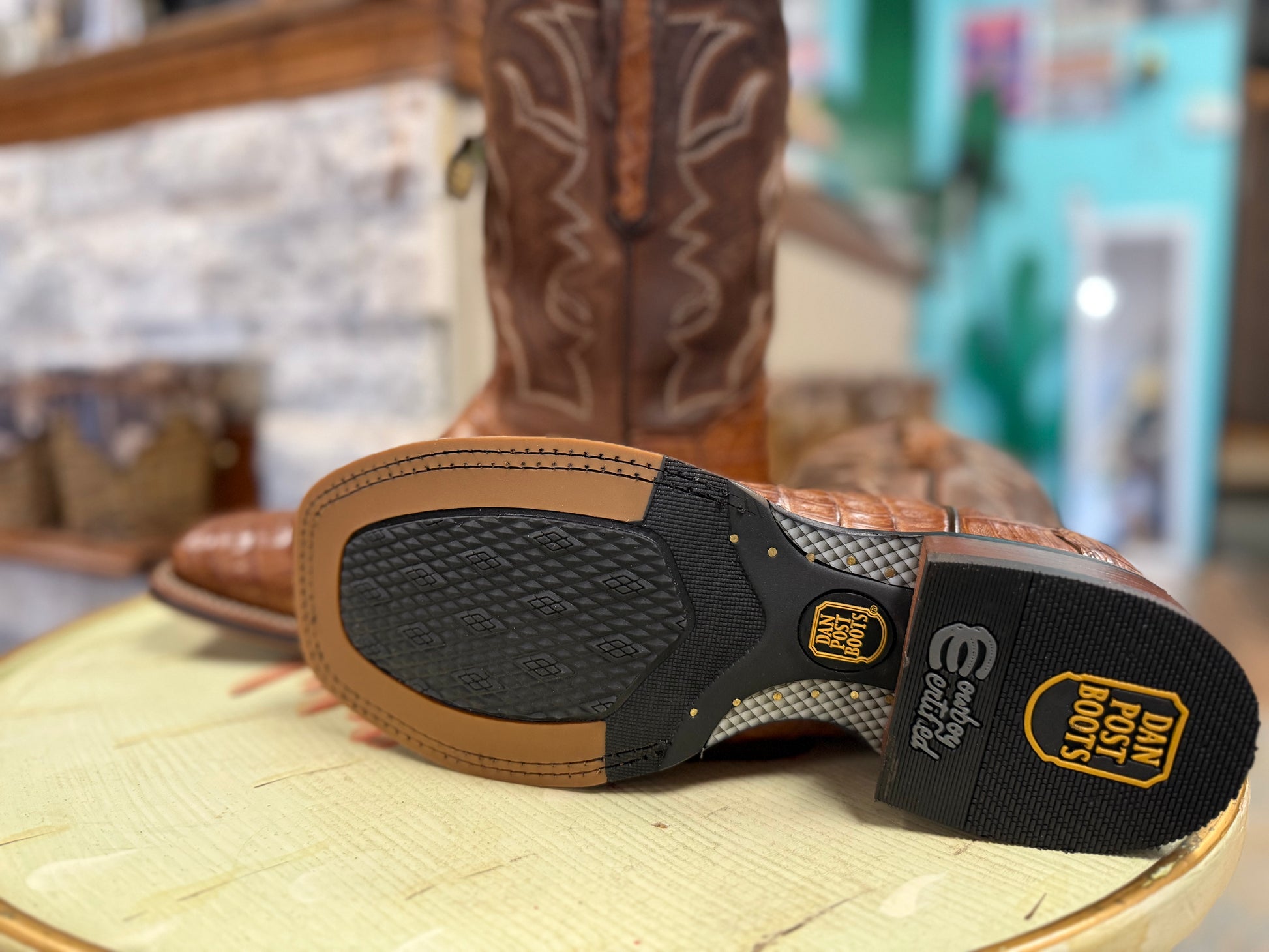 Close-up of a brown cowboy boot with a focus on the sole and brand logo.