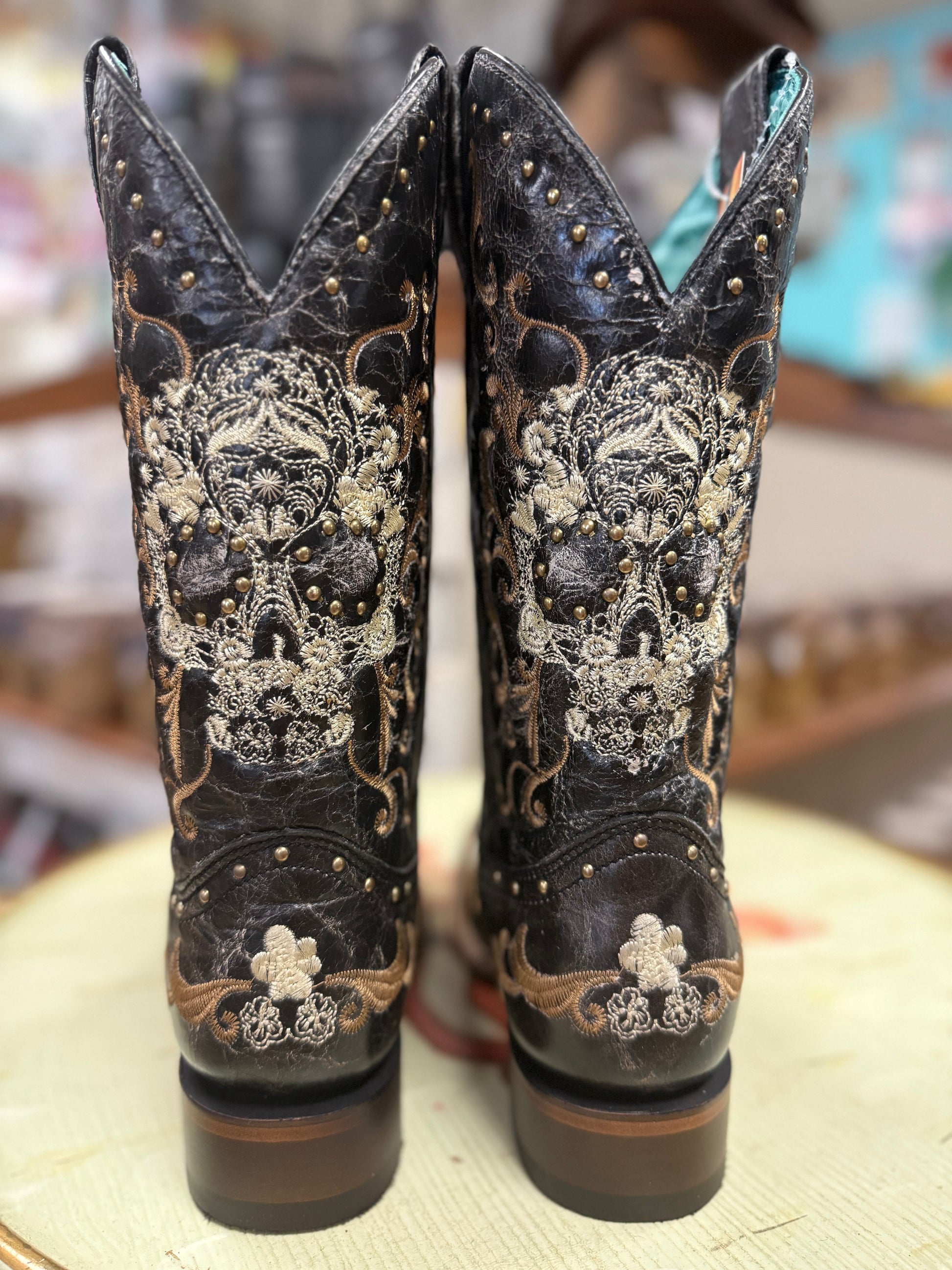Pair of black cowboy boots with intricate white embroidery on a blurred background