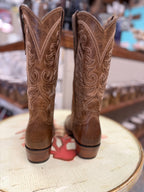 Pair of brown cowboy boots with intricate designs on a chair.