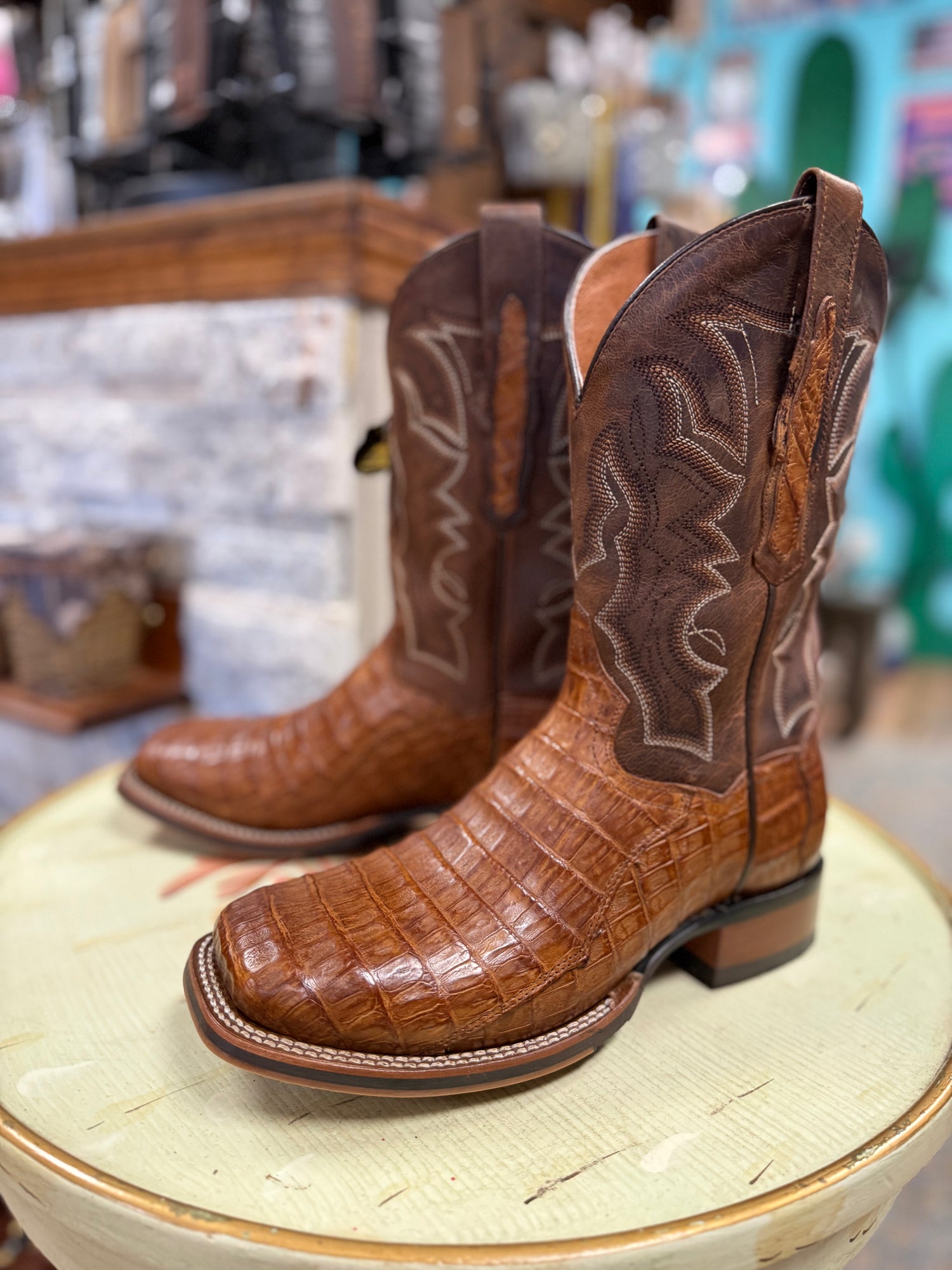 Brown cowboy boots with detailed design on a round surface in a store setting