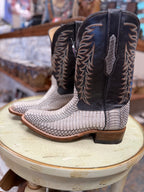 Pair of cowboy boots with intricate designs on a round stool.