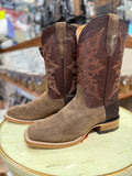Pair of brown and tan cowboy boots with intricate designs on a round surface.