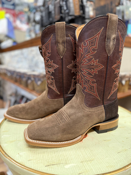 Pair of brown and tan cowboy boots with intricate designs on a round surface.