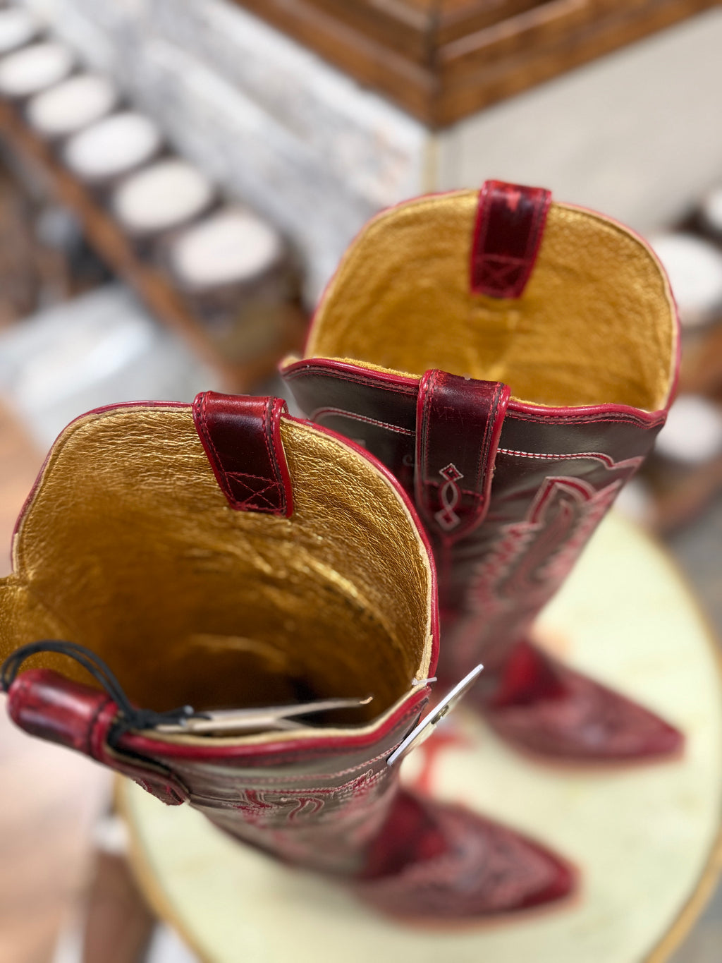 Close-up of a pair of cowboy boots with red accents on a blurred background