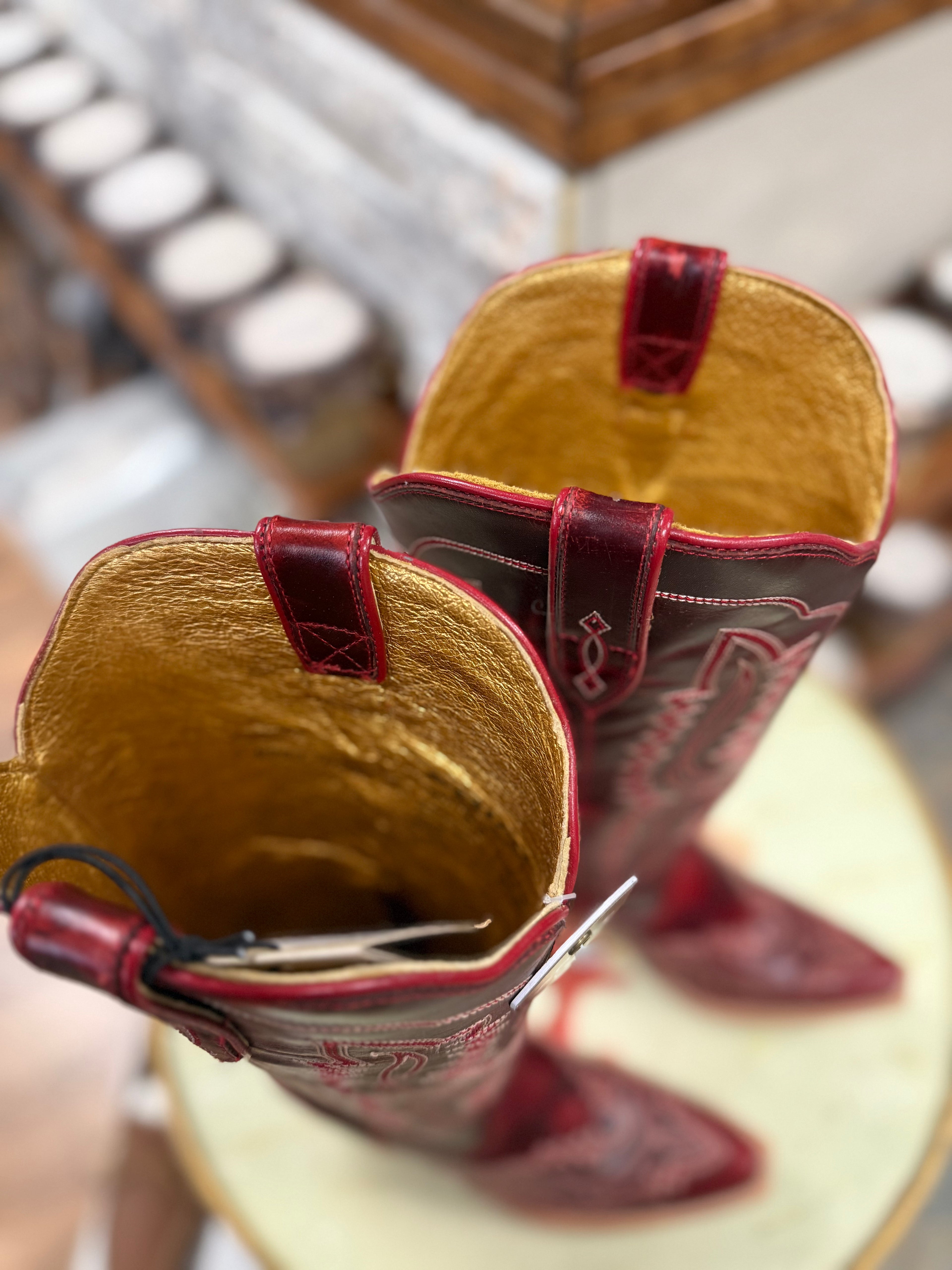 Close-up of a pair of cowboy boots with red accents on a blurred background