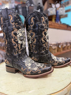 Pair of black cowboy boots with intricate gold embroidery on a wooden surface.