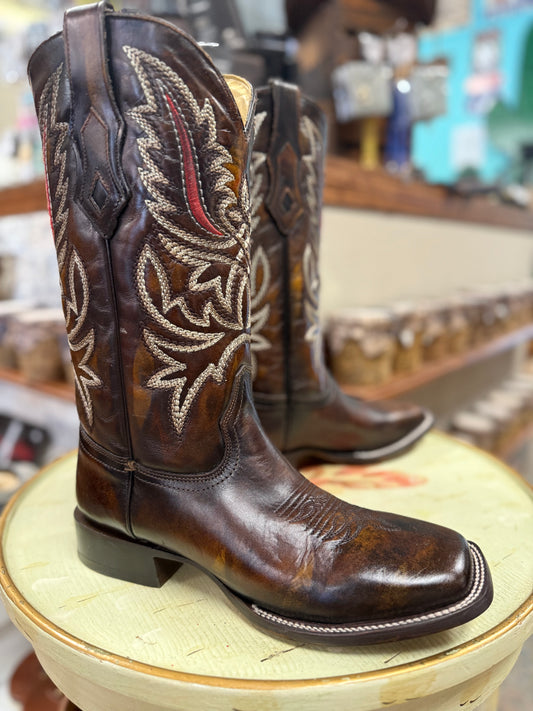 Brown cowboy boots with intricate white stitching on a green stool.