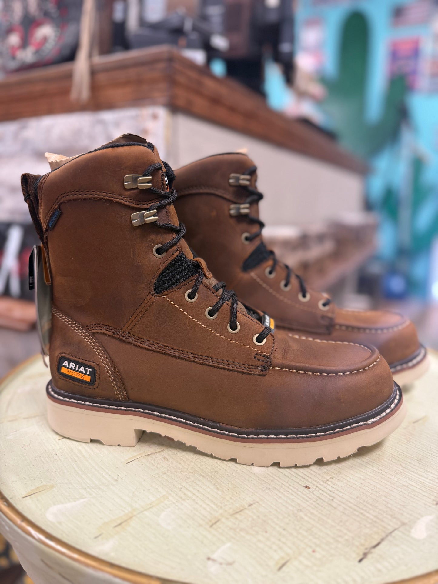 Pair of brown Ariat boots on a wooden surface with a blurred background