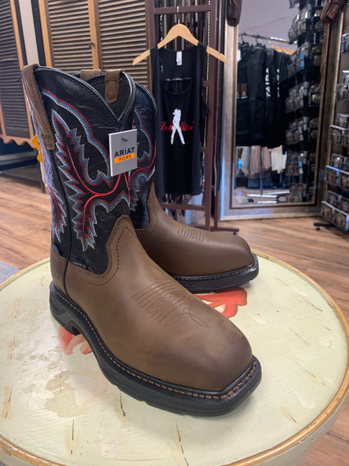 A pair of brown, waterproof work boots with a carbon toe and a low heel, displayed on a wooden platform inside a retail store.