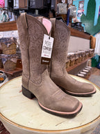 Pair of brown Ariat boots on a round surface with a store interior background.