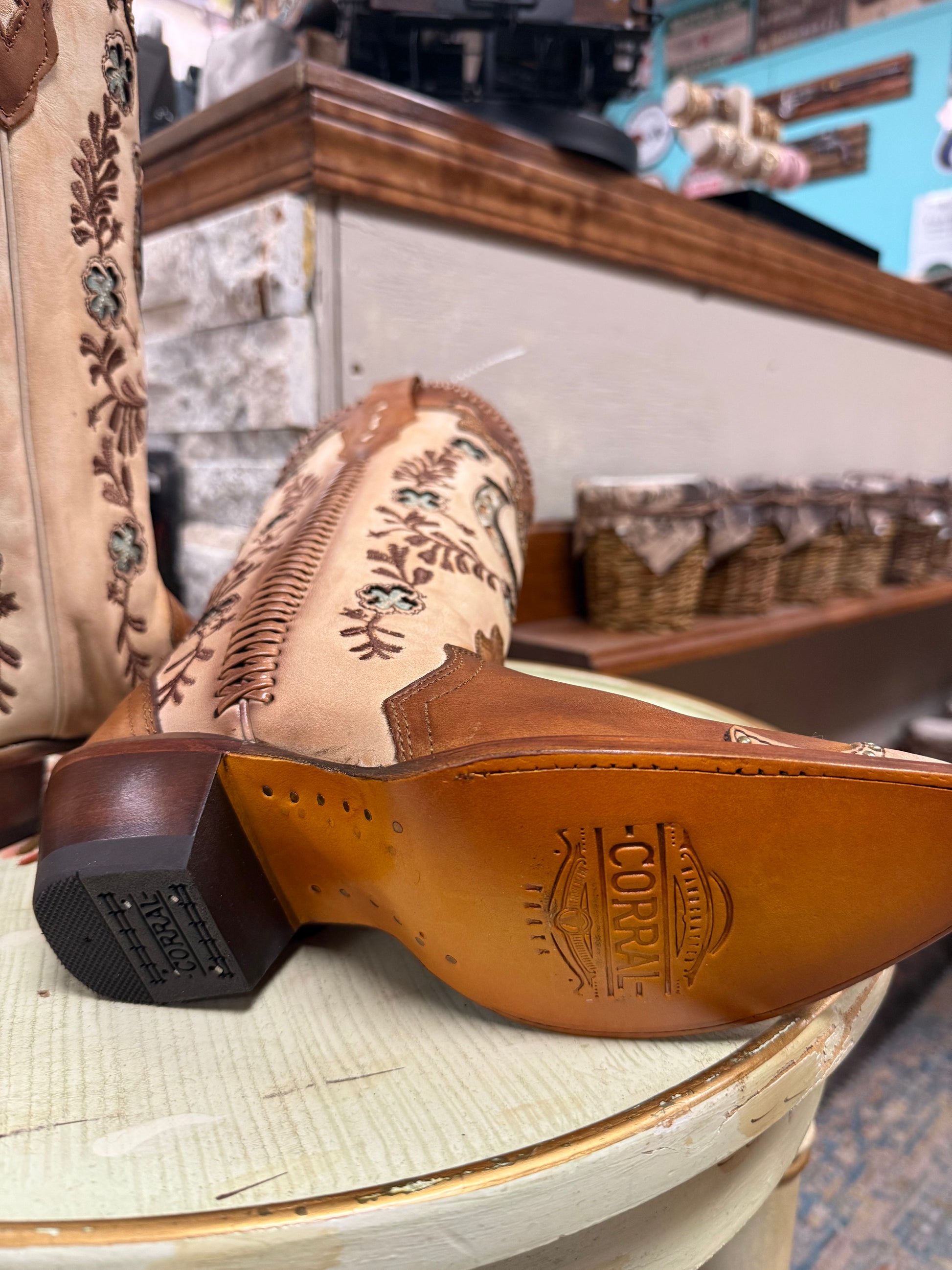 Close-up of a pair of cowboy boots with intricate designs on a wooden stool.