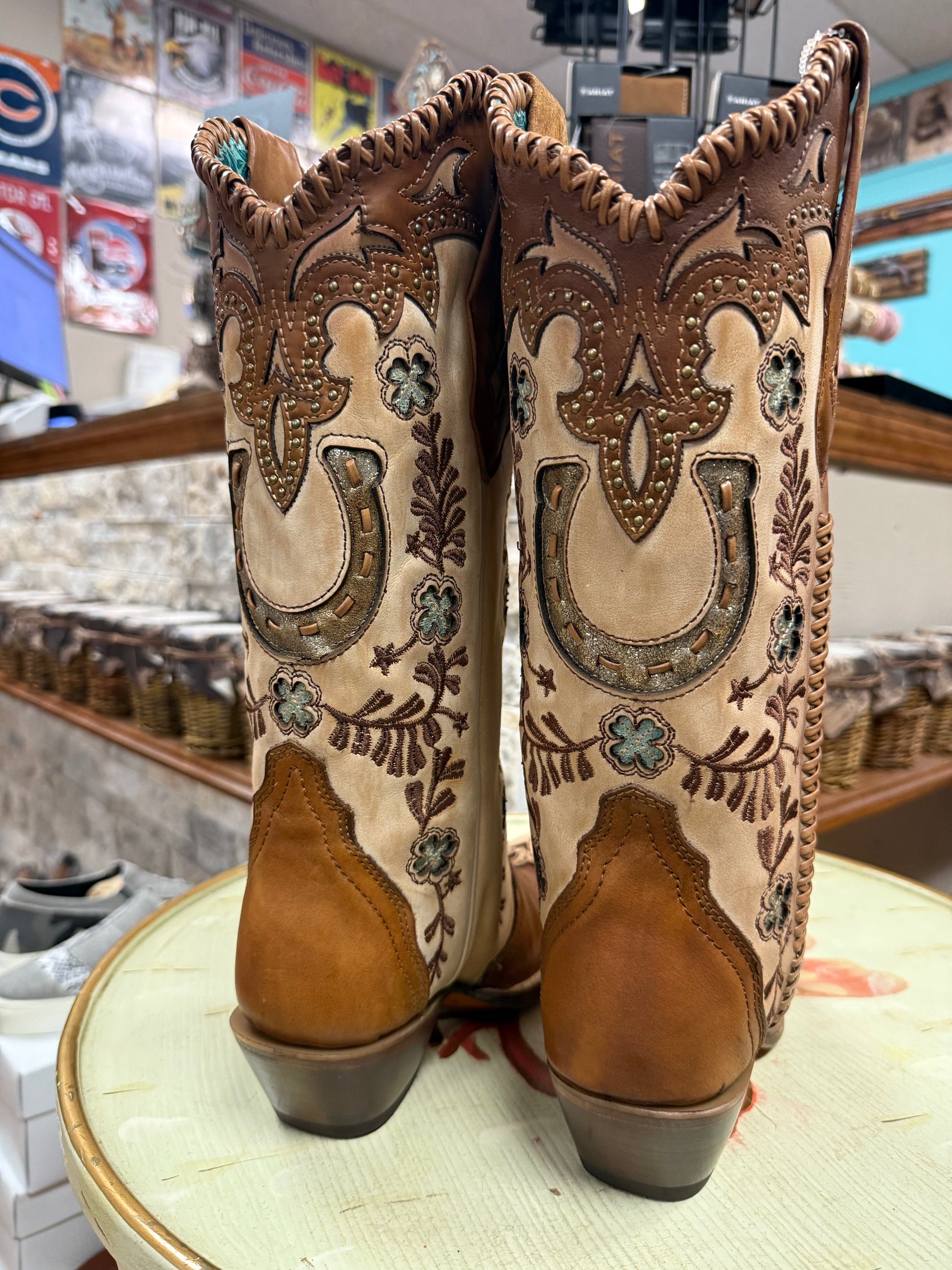 Pair of brown cowboy boots with intricate designs on a store shelf.