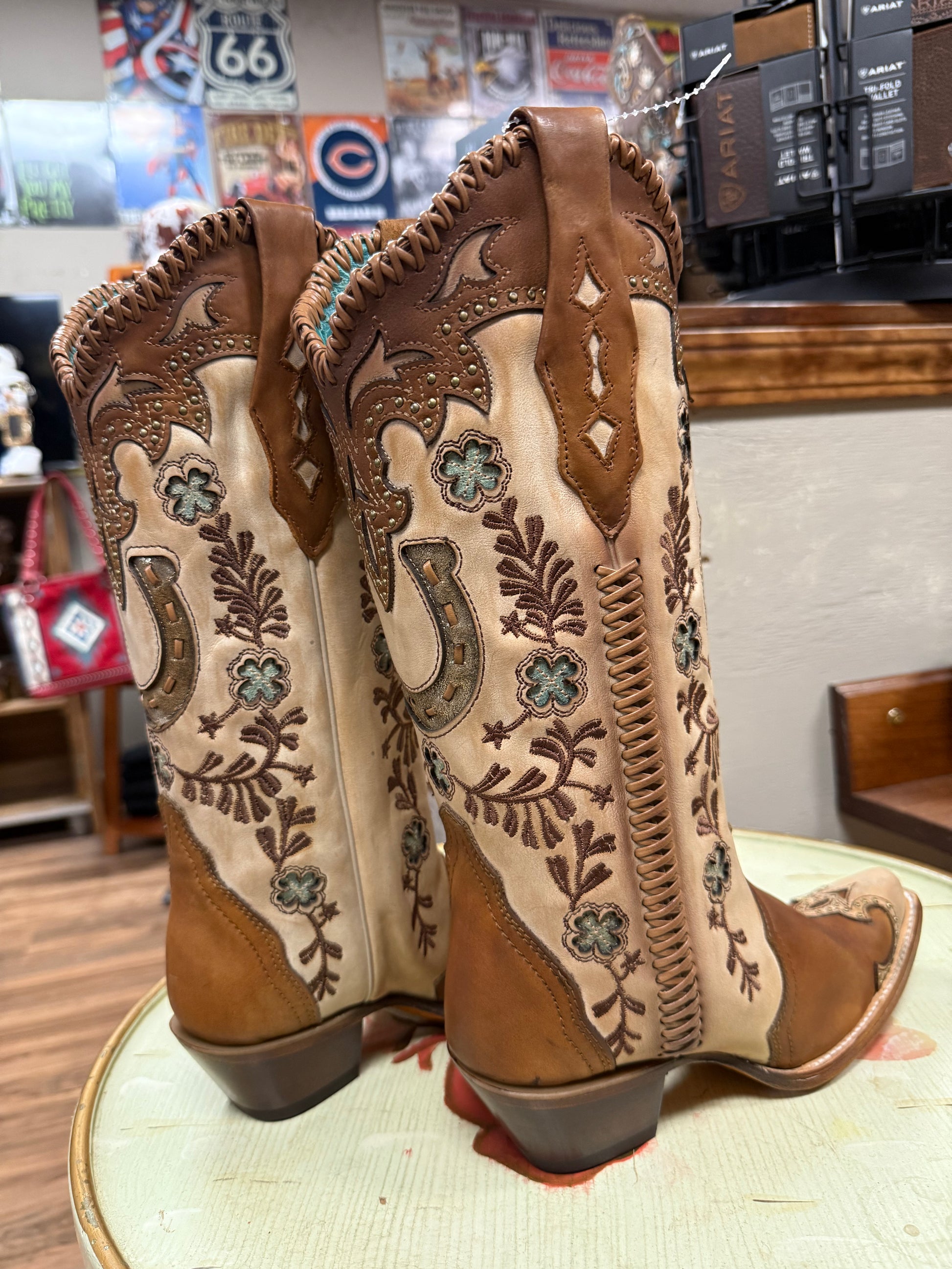Pair of brown and beige cowboy boots with intricate designs on a table.