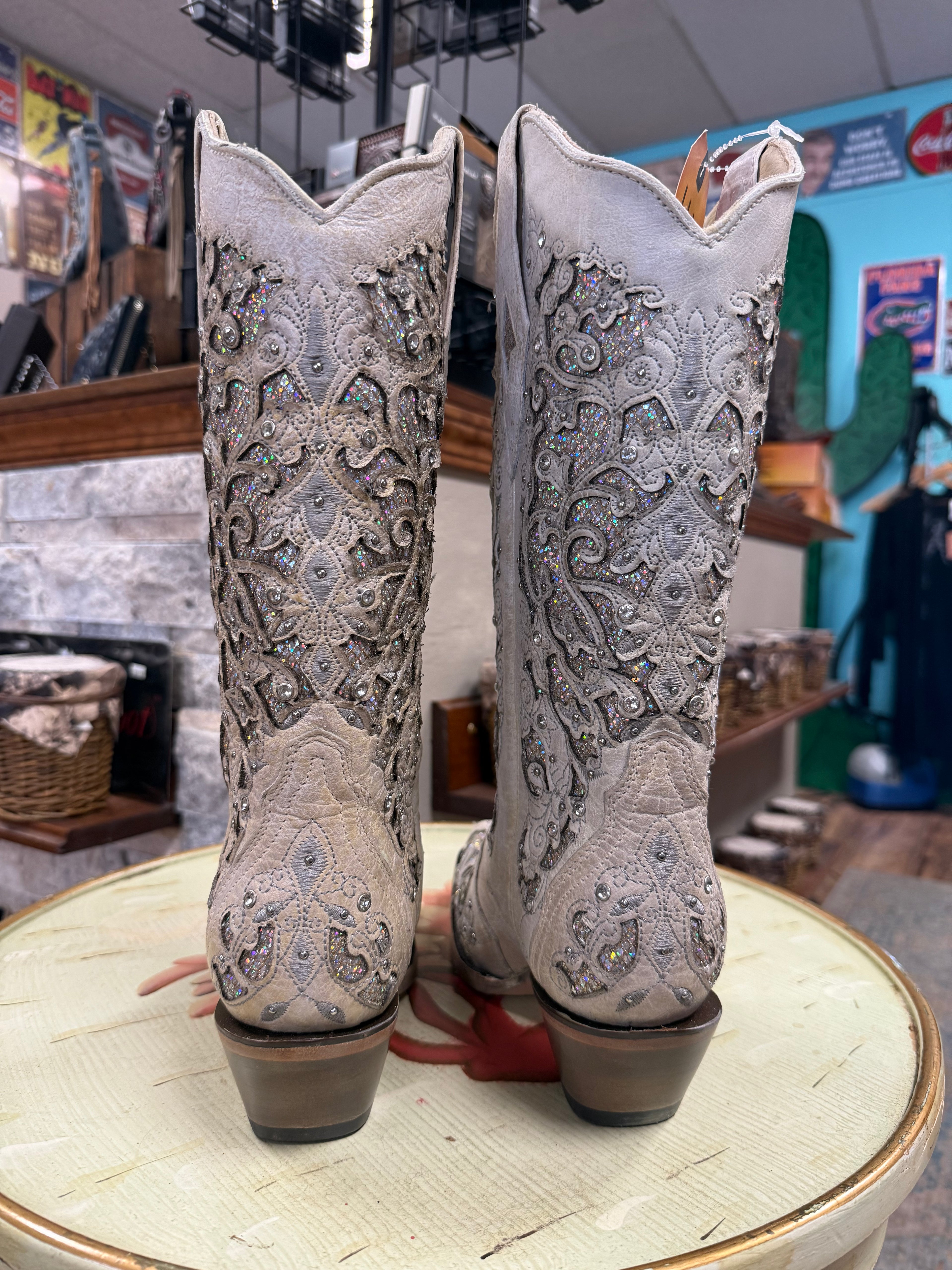 Pair of ornate cowboy boots on a round table with a store interior background.