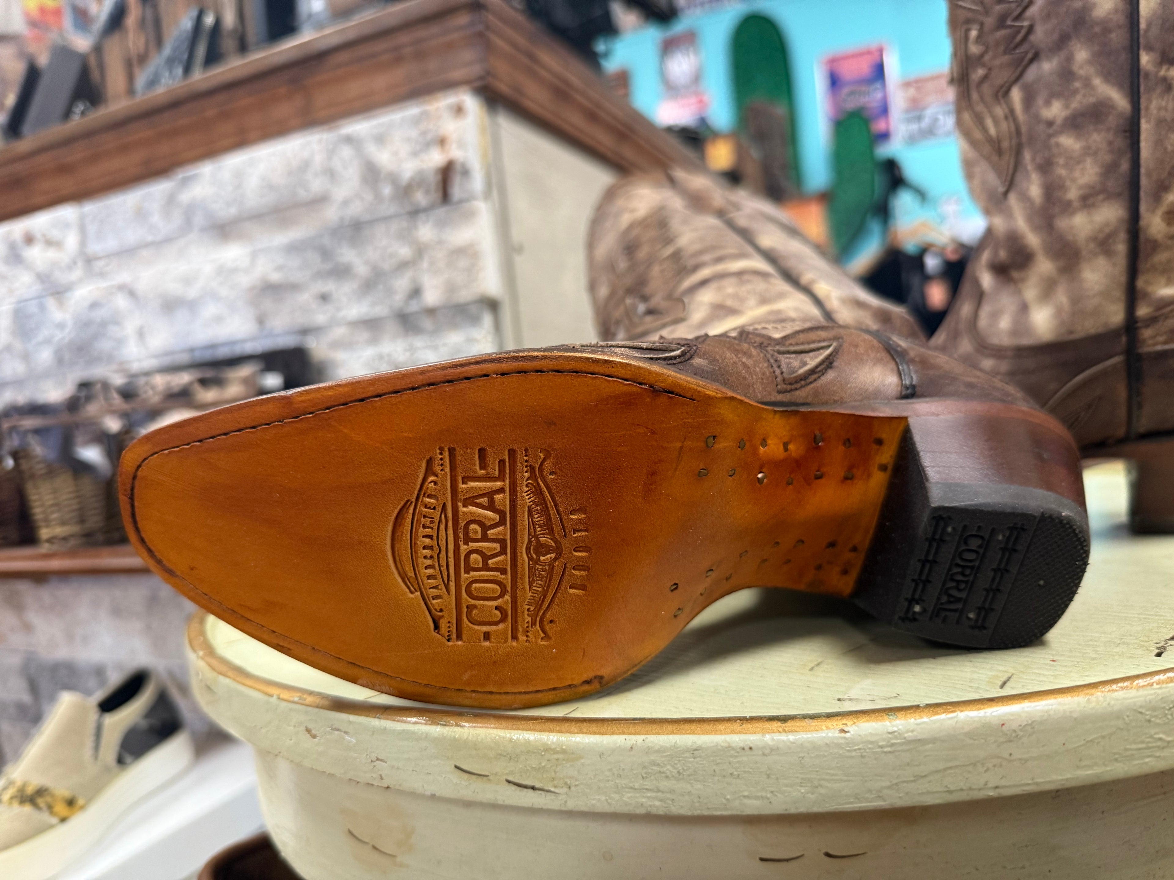 Brown leather boot sole with 'Corral' branding on a wooden surface.