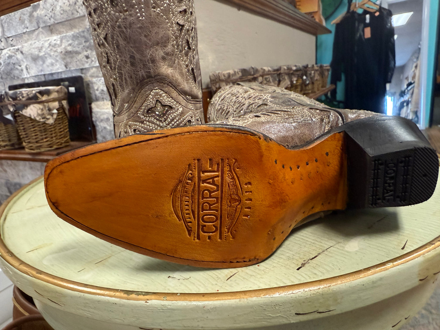 Close-up of a brown leather boot sole with 'Corral' branding on a light green surface.