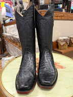 Pair of black cowboy boots on a round surface with a store interior background